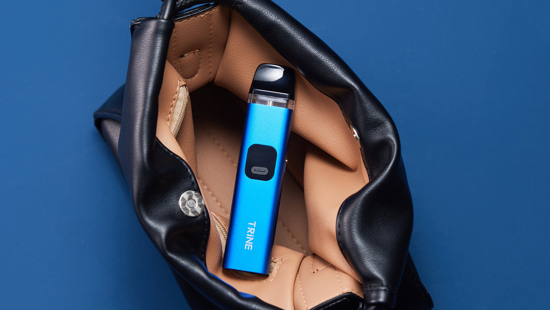 Innokin Trine refillable vape in a sleek blue design placed inside an open black leather bag with beige interior, displayed on a solid blue background for a stylish and modern look.