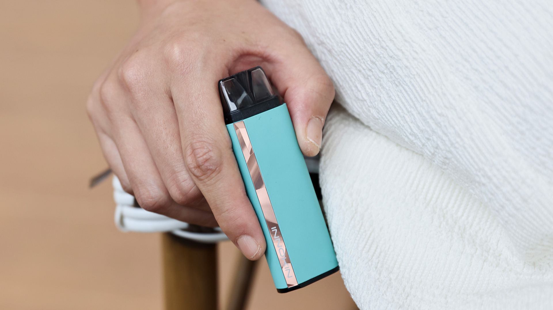 Person holding a turquoise Innokin Klypse pre-filled pod vape in hand.