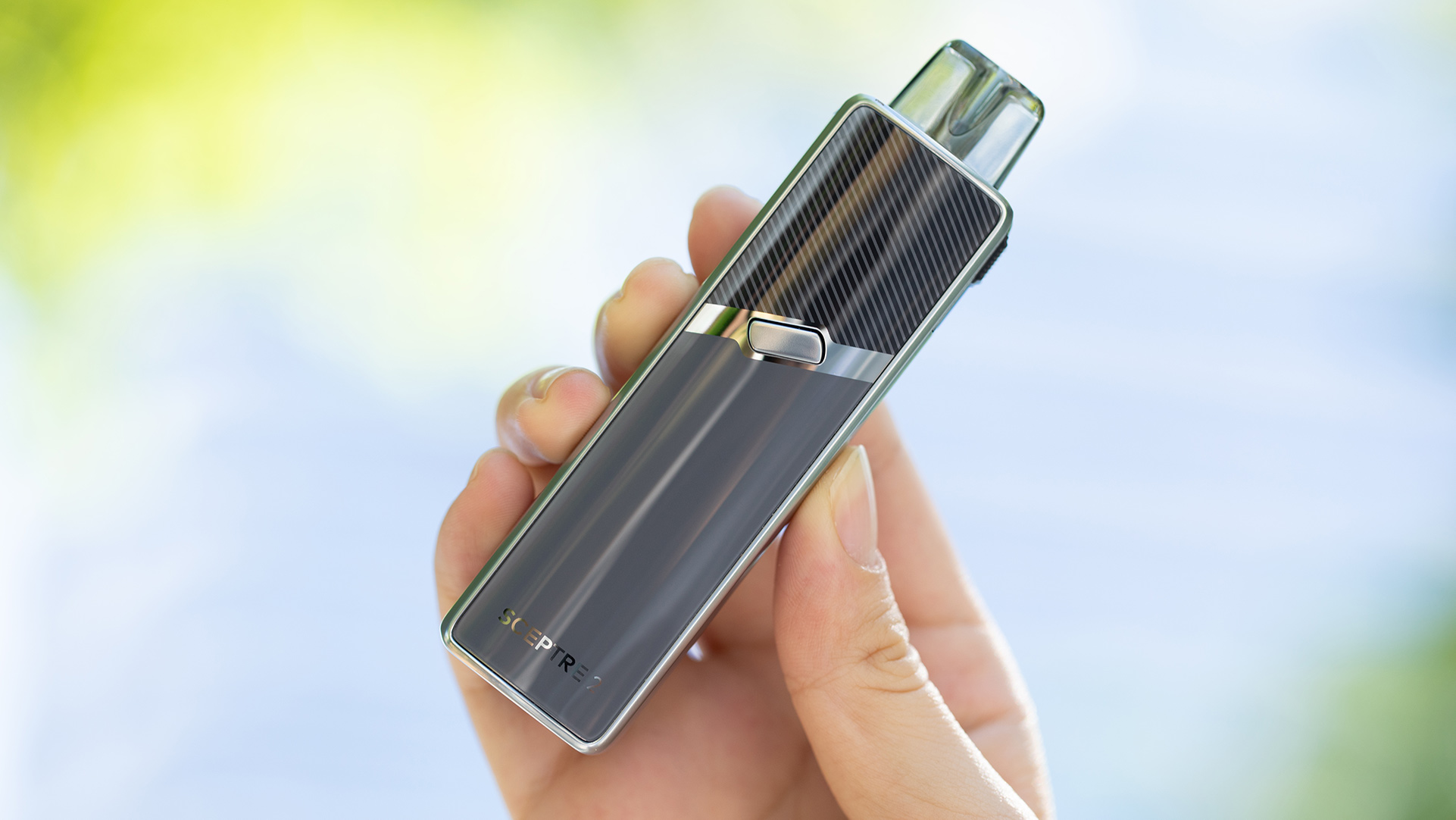 A hand holds the sleek Innokin Sceptre 2 vape device, designed for nicotine salts, against a softly blurred green and blue background.