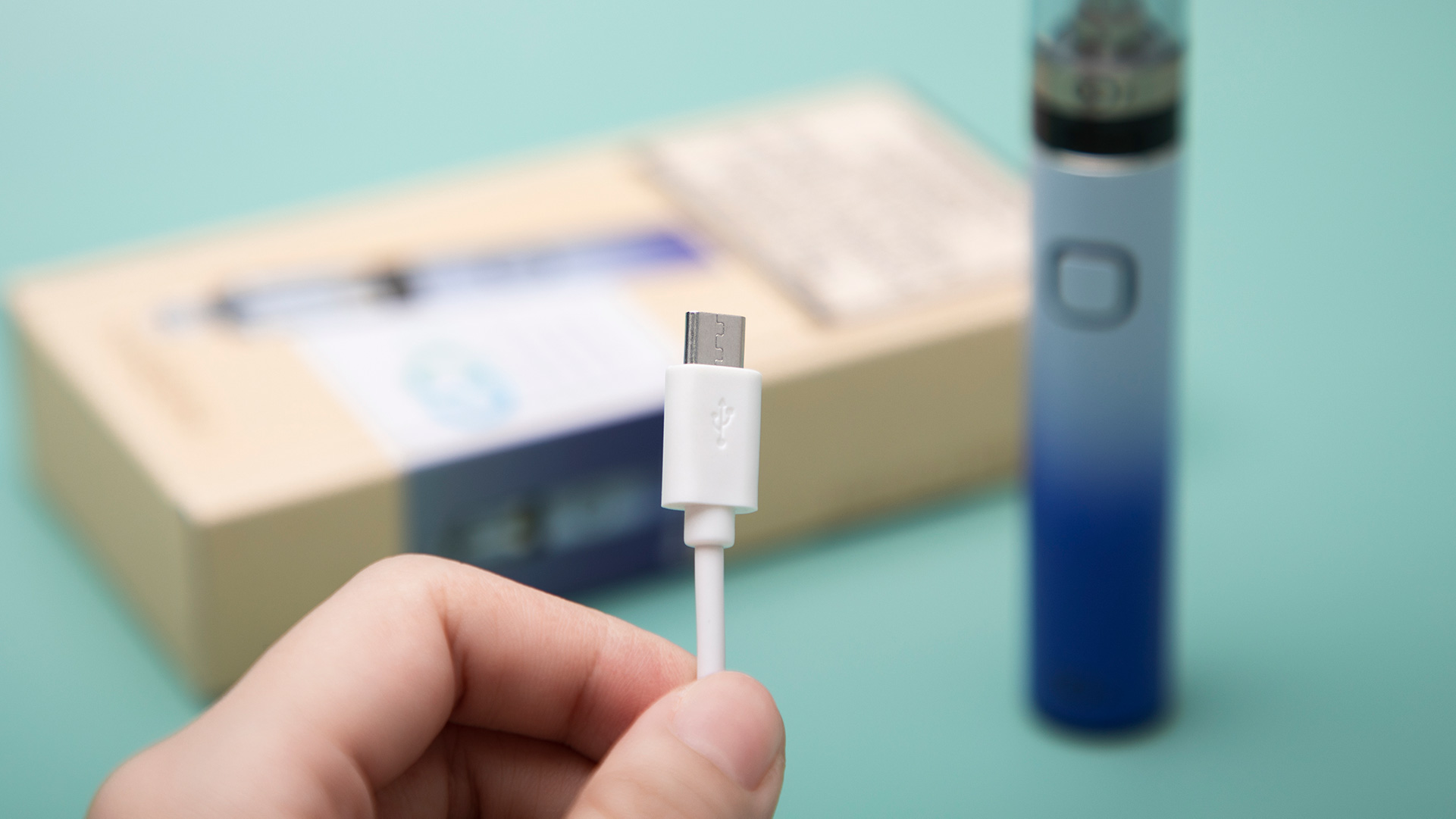 Close-up of vape pen charger being held, addressing charging issues.