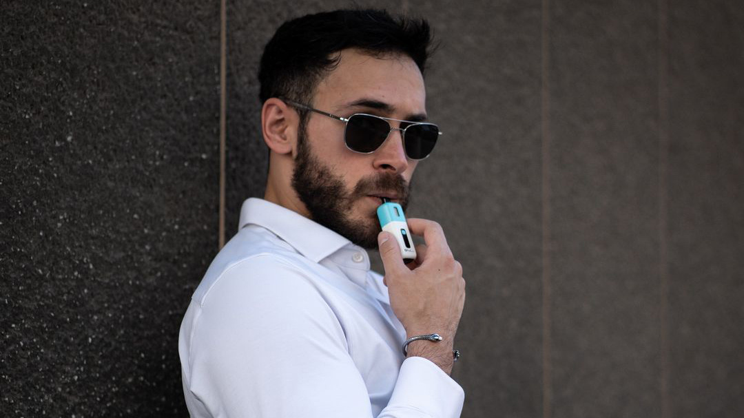 Stylish man using Z Pod Nano, recommending refillable vapes for heavy smokers